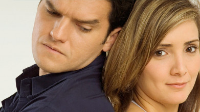 Close-up of faces of husband and wife standing back to back. He’s looking over his shoulder frowning, she looks neutral.