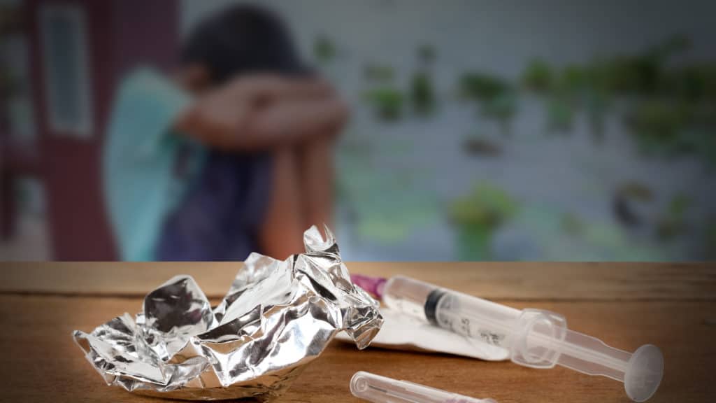 Opioid Syringe On A Table With A Man Out-Of-Focus in the background