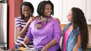 A mother with her two daughters cooking at home in their kitchen