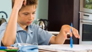 Discouraged boy trying to do his homework at a dining table