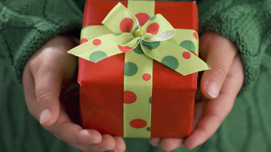 Close up of a child's hands holding a small, wrapped present
