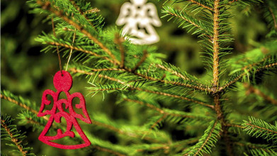 An ornament of an angel hangin on a Christmas tree