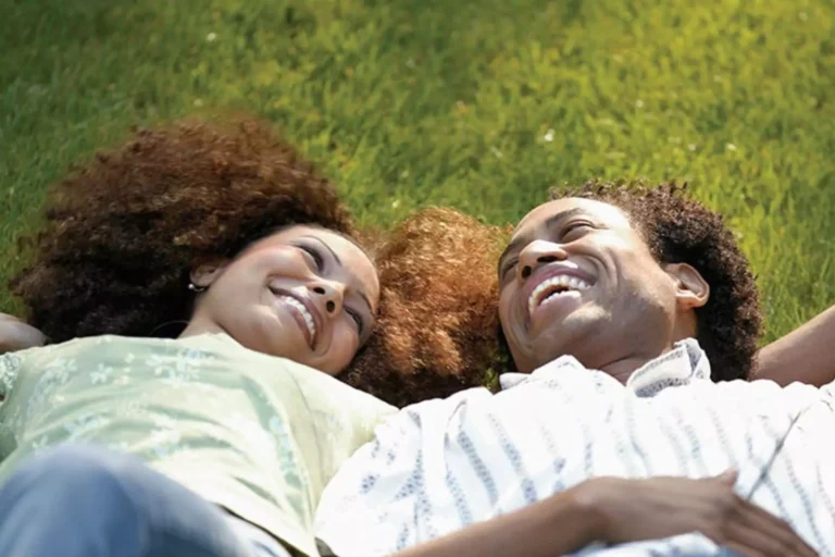 A happy couple lying on the grass, looking at each other with smiles, symbolizing that they've unlocked the secrets to a lifelong love.