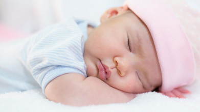 Close up of a cute, baby Asian girl sleeping on her stomach with her head resting on her forearms