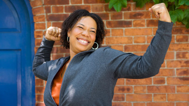 A smiling, happy African-American woman flexing her arm muscles to express a triumphant spirit or a joyful moment