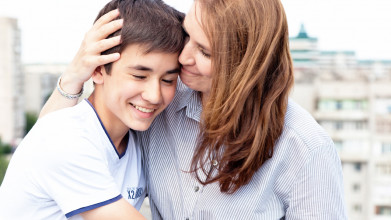 Mom giving her smiling teen son an affectionate side hug