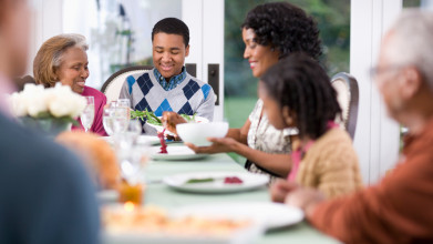 Happy African-American family seated around the dining room table, having a meal