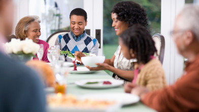 Happy African-American family seated around the dining room table, having a meal