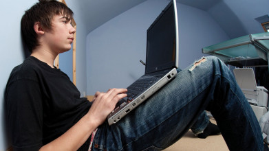 Teenage boy sits staring at his laptop screen