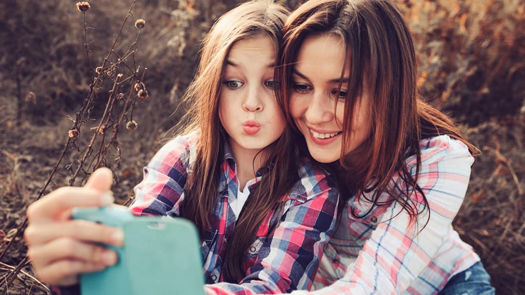 mother and daughter making selfie outdoors