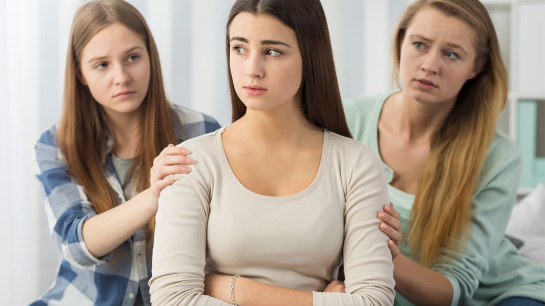 Thoughtful female teenager being supported by two worried friends because abortion is the path of least resistance.