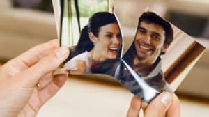 Close up of hands holding a photo ripped down the middle, separating a happy husband and wife, suggesting divorce