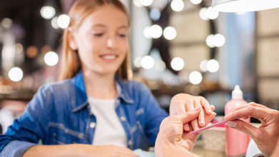 Smiling tween girl having her nails done