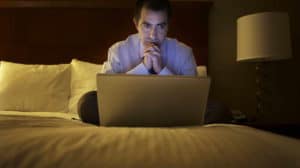 Man looking at computer in hotel room