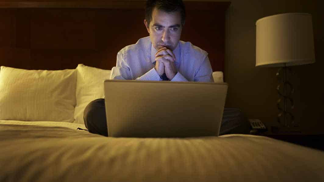 Man looking at computer in hotel room