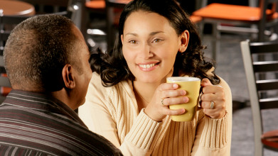 Married couple enjoying coffee in a coffee shop, with the focal point of the image on the smiling wife