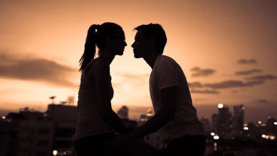 A man and woman kiss at sunset