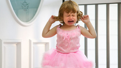 Upset toddler girl in a pink dress