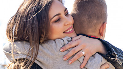 Close-up of mom smiling as she's hugging her young son