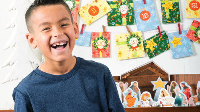 young kid standing in front of a wall of Christmas cards