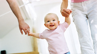 Close up of happy young child holding her dad's and mom's hands as they show her parental love