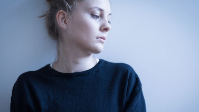 Somber woman staring at something off camera against a gray background