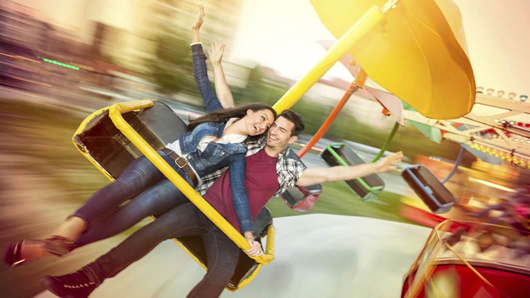 Laughing husband and wife having fun while riding a flying merry-go-round