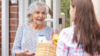 A young woman delivering groceries to her elderly woman neighbor