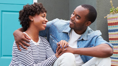 Smiling husband and wife sitting together on their front porch step