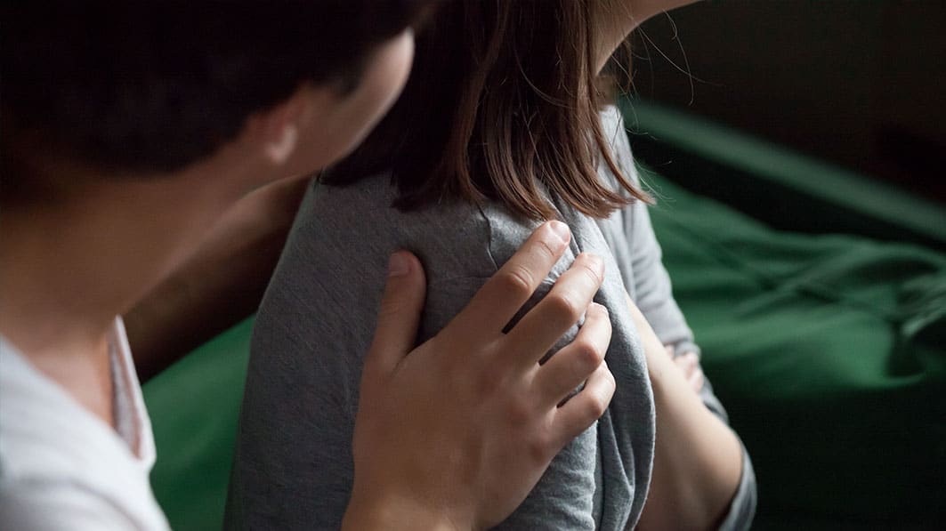 Husband trying to talk to his wife; his hands are on her shoulders and she's looking away