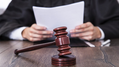 Close-up of judge's hands holding a paper, with a gavel in the foreground