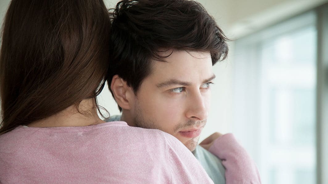 Husband hugging wife looking away concerned