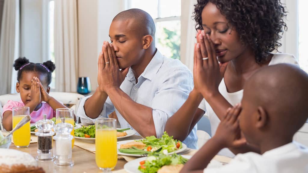 Young family praying before their meal