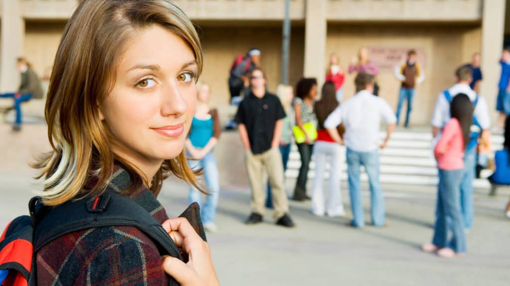 A student heads into school with peers in the background