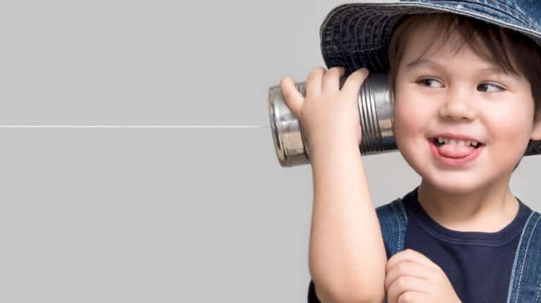 Little boy holding a can with a cord to his ear and listening