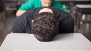 A student with head on school desk, face down