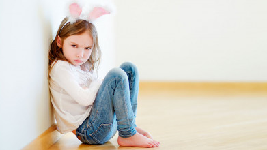 An angry daughter sits on the floor