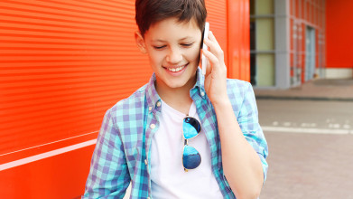 A young boy talks on his phone in the city