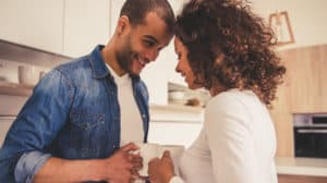 Couple in kitchen, facing each other and touching foreheads