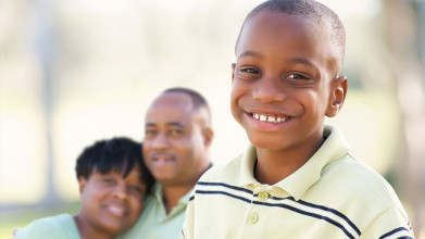 Young son smiling with parents in the background