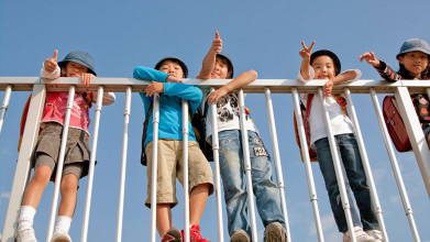 Kids need boundaries as seen by several kids standing at the fence and not falling