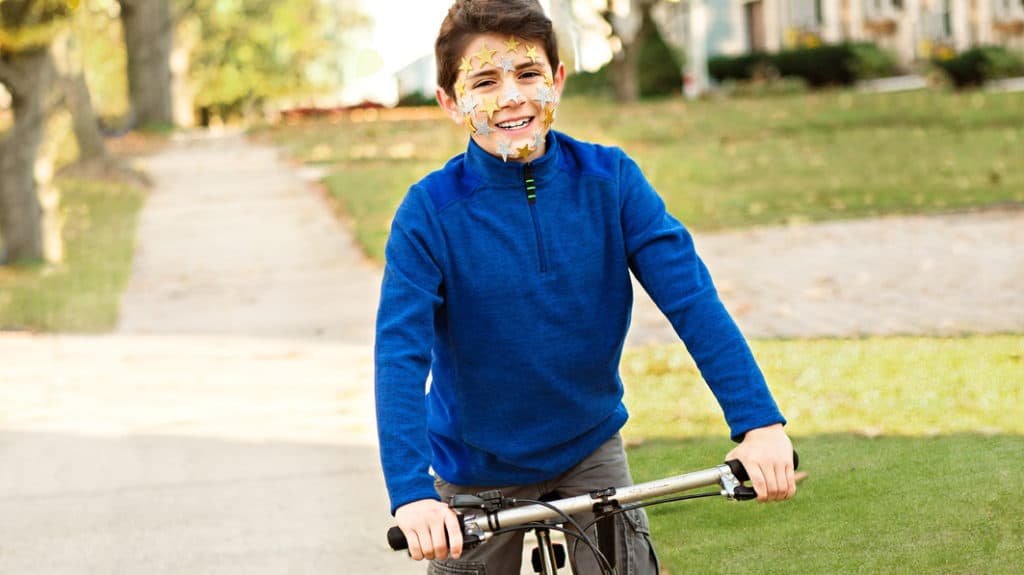 Healthy identity as seen by a smiling boy on a bike with star stickers on his face