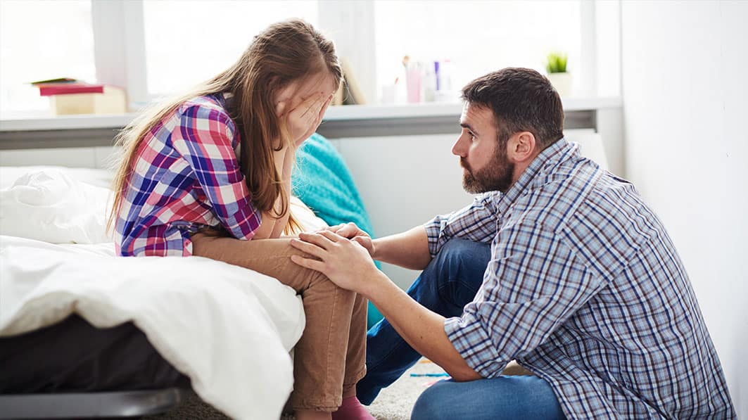 Father tries to console crying teen daughter