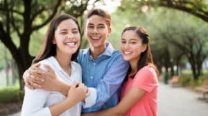 Three teen siblings hug each other and smile for photo