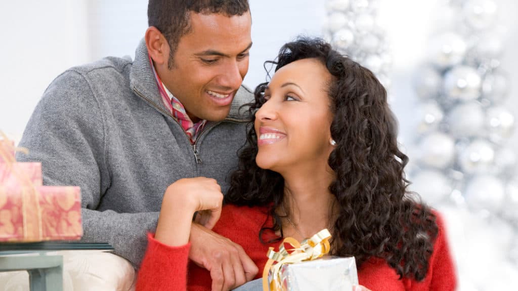 Husband And Wife Affectionately Exchanging Christmas Gifts