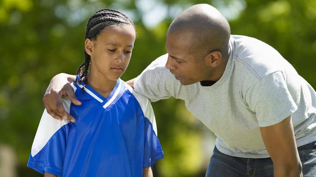 Dad giving a pep talk to his upset teen athlete