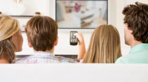 Boy holds remote control at family watches TV together