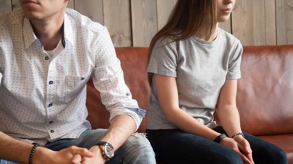 Emotionally disconnected couple sits on couch