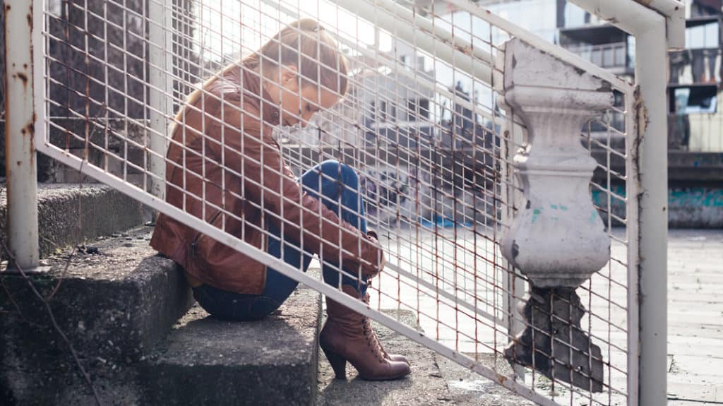 sad young woman sitting alone on steps