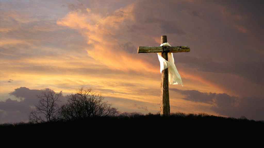 Picture of an empty crucifixion cross on a hill with sunrise in background